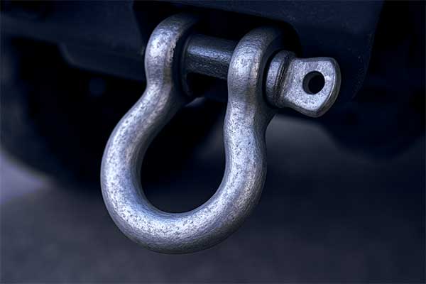 A close-up of a galvanized tow shackle connected to a vehicle's recovery point.