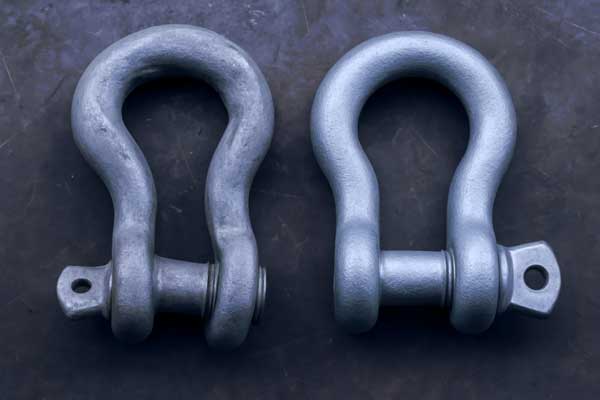 A dangerously deformed shackle next to a new one after being overloaded