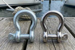 A shiny galvanized shackle next to a stainless steel shackle