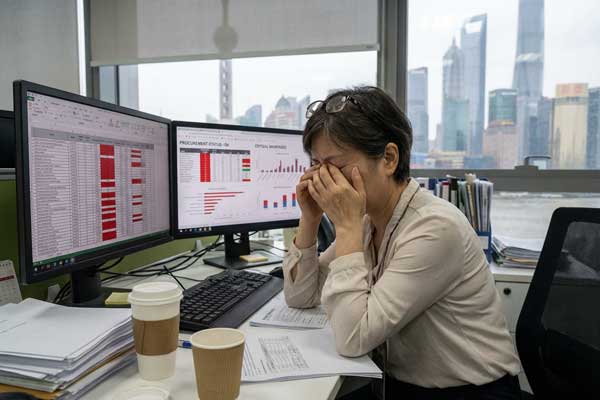 A procurement manager looking stressed at a computer screen with spreadsheets